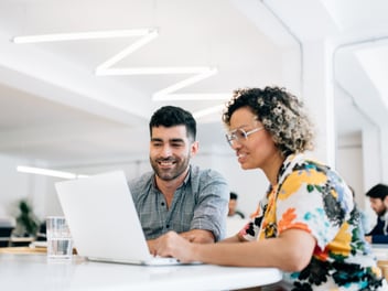 A woman and a man looking at a laptop
