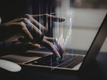 A person typing on a laptop with data graphics