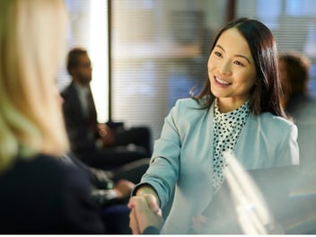 A woman shaking hands with someone and smiling
