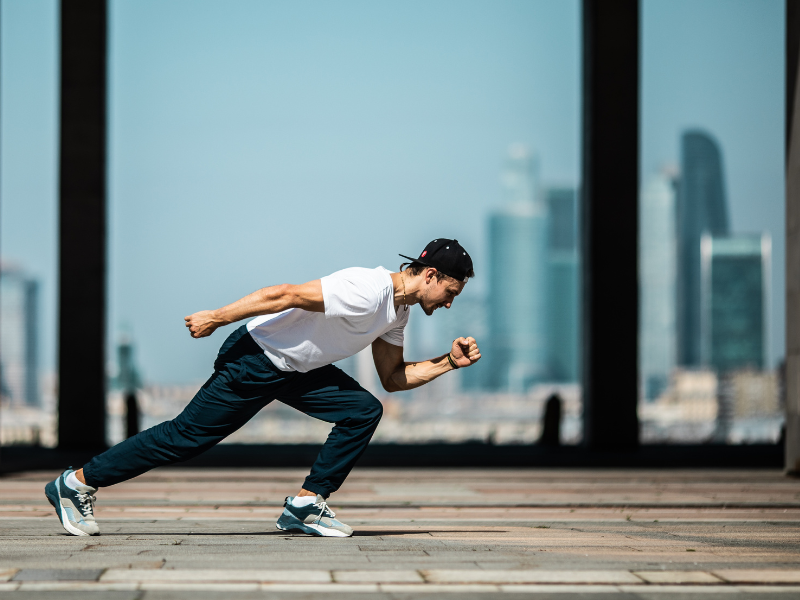 A man in sprint position with a corporate backdrop to signify pace